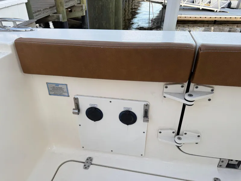 Slide: The Image of 2021 Scout 330 LXF boat interior with brown seating and utility panel. - 79
