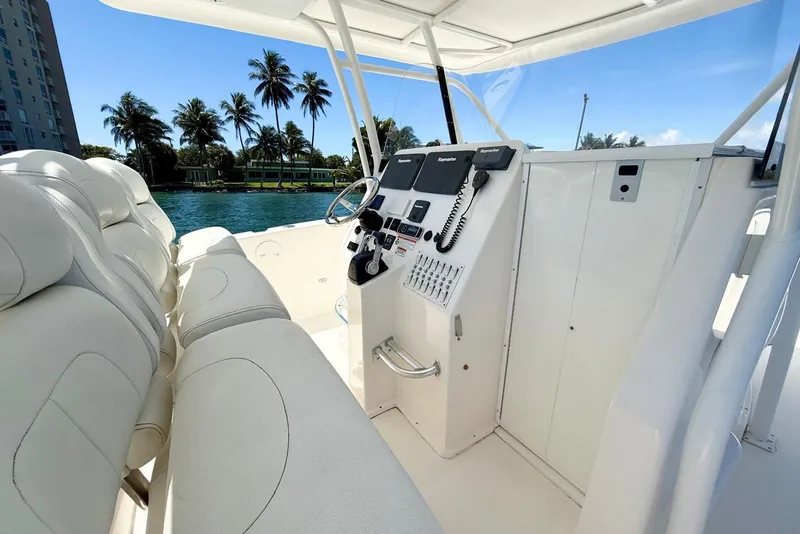 Slide: The Image of 2014 Stamas 390 Tarpon boat interior with helm, white seating, and palm trees in background. - 17