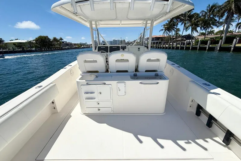 Slide: The Image of 2014 Stamas 390 Tarpon boat interior with seating and storage, docked by palm trees. - 22