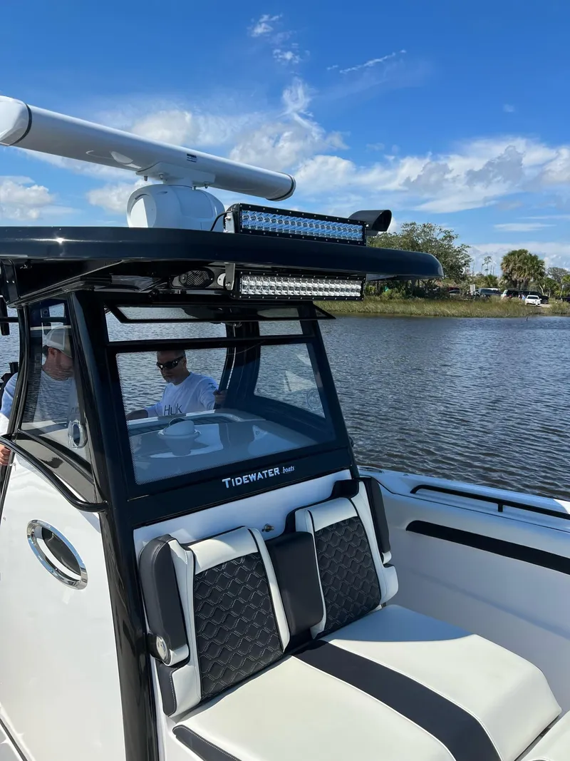 Slide: The Image of 2023 Tidewater 320 CC Adventure boat on a calm lake under a clear blue sky. - 17