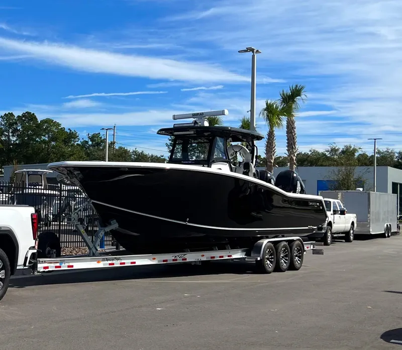 Slide: The Image of 2023 Tidewater 320 CC Adventure boat on trailer, parked outdoors under blue sky. - 3