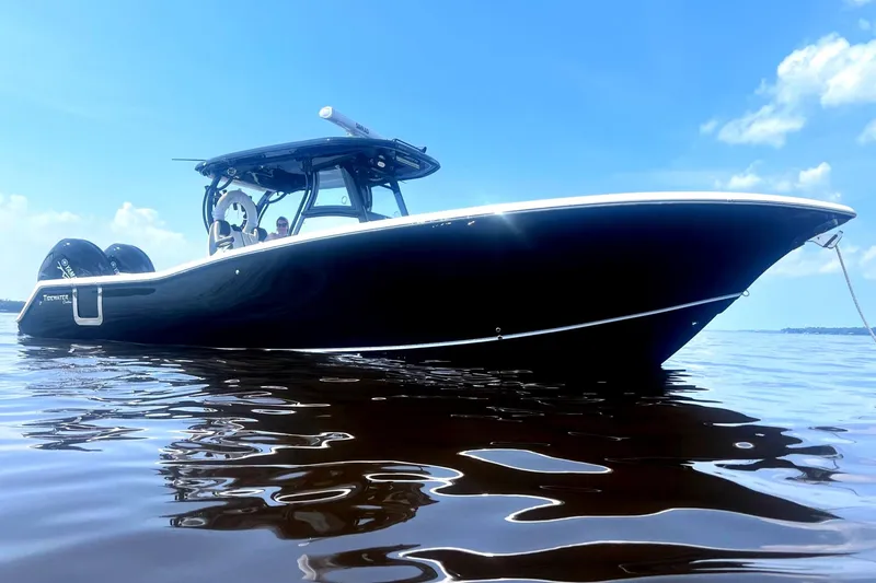 Slide: The Image of 2023 Tidewater 320 CC Adventure boat on calm water under a clear blue sky. - 4