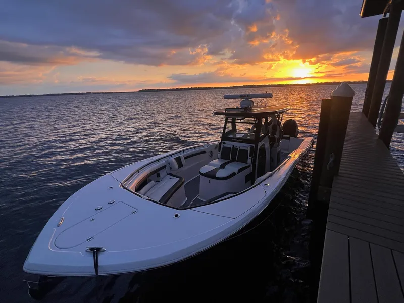 Slide: The Image of 2023 Tidewater 320 CC Adventure boat at sunset by the dock. - 5