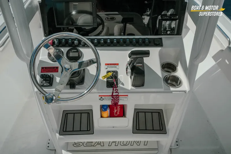 Slide: The Image of 2021 Sea Hunt Ultra 229 boat dashboard with steering wheel, controls, and cup holders. - 12