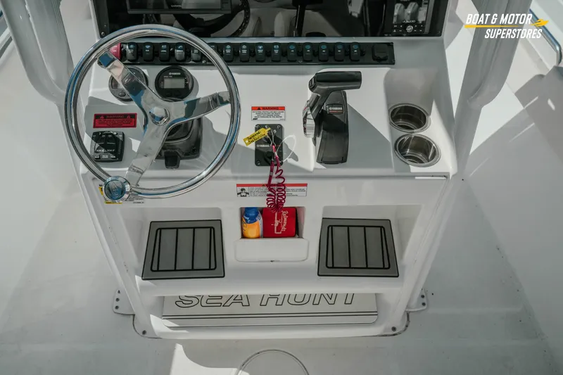 Slide: The Image of 2021 Sea Hunt Ultra 229 boat console with steering wheel, controls, and cup holders. - 13