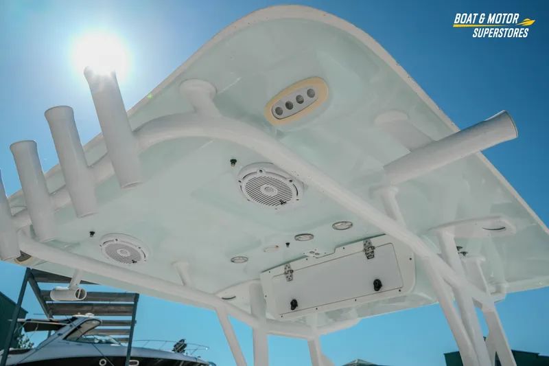 Slide: The Image of 2021 Sea Hunt Ultra 229 boat T-top with rod holders and speakers under clear blue sky. - 14