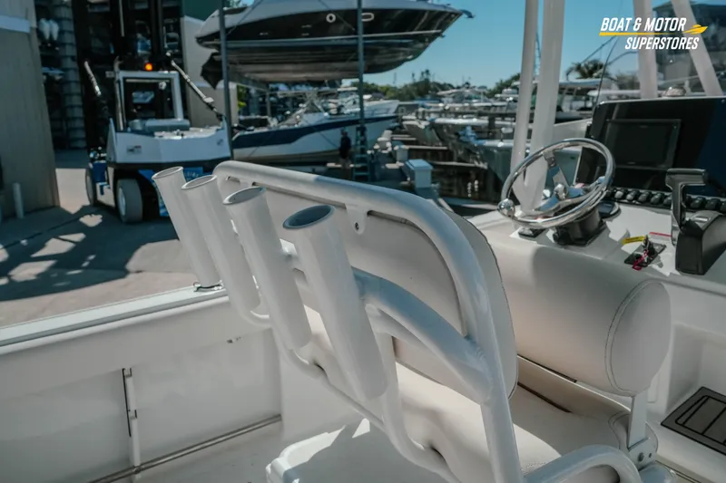 Slide: The Image of 2021 Sea Hunt Ultra 229 boat interior with steering wheel and rod holders at marina. - 16