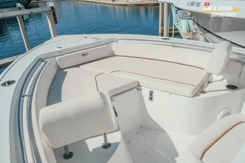 Slide: The Image of 2021 Sea Hunt Ultra 229 boat interior with white seating, docked by the water. - 28