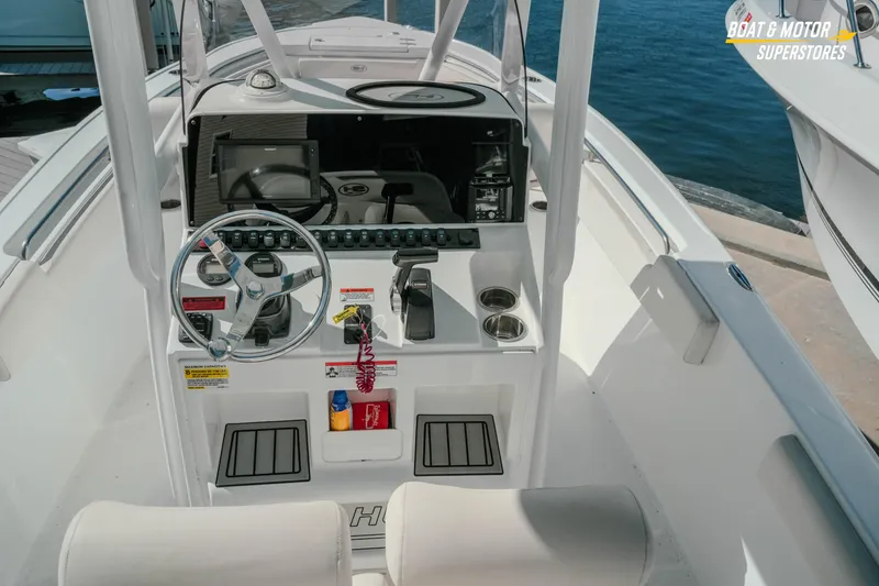 Slide: The Image of 2021 Sea Hunt Ultra 229 boat cockpit with steering wheel and controls, docked by the water. - 7