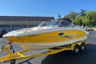 The Image of 2008 Chaparral Sunesta 224 boat on trailer, yellow and white design, parked outdoors. - 0