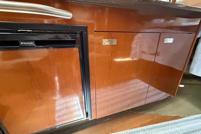 Slide: The Image of 2012 Sea Ray Sundancer 350 interior with Dometic fridge and wooden cabinetry. - 13