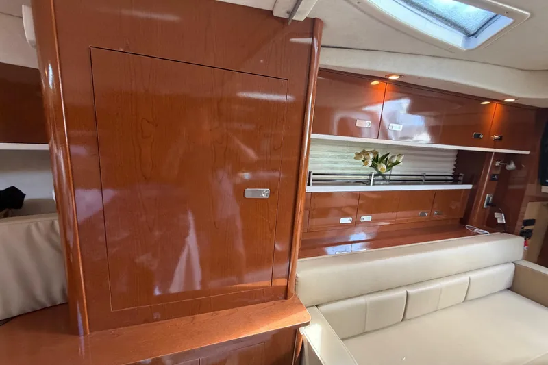 Slide: The Image of Interior of 2012 Sea Ray Sundancer 350 with polished wood cabinetry and beige seating. - 21