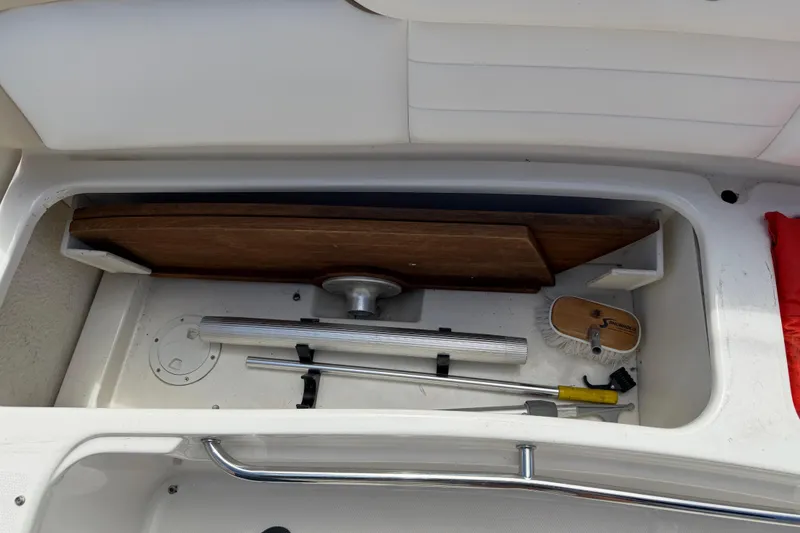 Slide: The Image of Storage compartment on a 2012 Sea Ray Sundancer 350 with cleaning tools and wooden panel. - 24