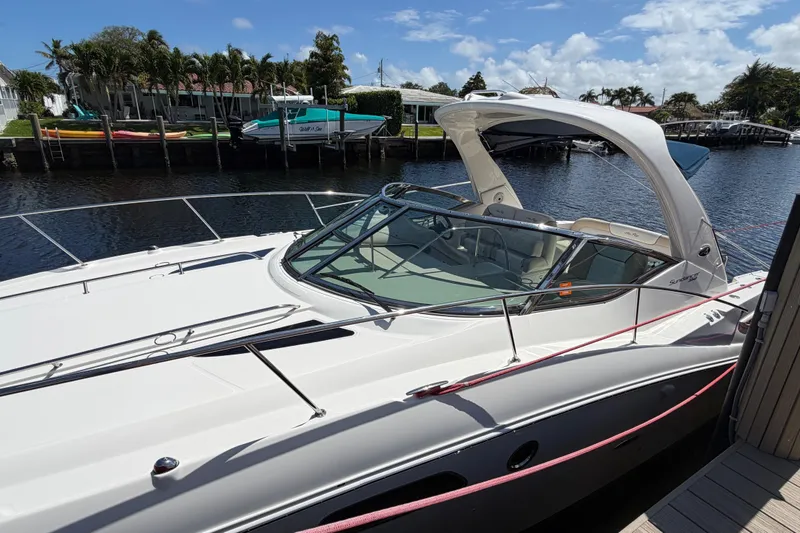 Slide: The Image of 2012 Sea Ray Sundancer 350 yacht docked by a scenic waterfront with palm trees. - 3