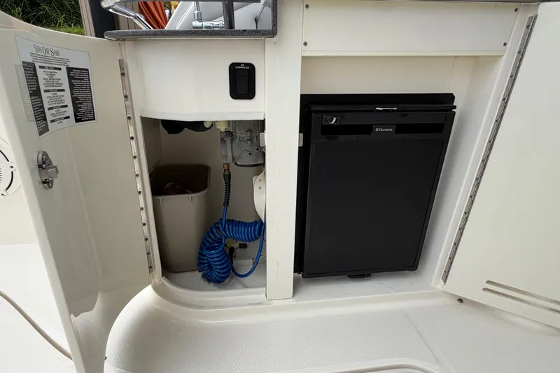 Slide: The Image of 2012 Sea Ray Sundancer 350 interior storage with mini fridge and coiled hose. - 44