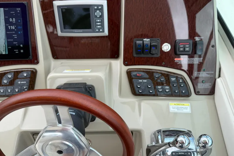 Slide: The Image of Control panel of a 2012 Sea Ray Sundancer 350 with steering wheel and navigation displays. - 49
