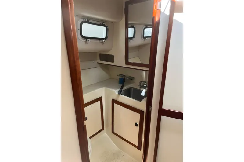 Slide: The Image of Interior of 1998 Albin 28 Tournament Express boat, featuring a compact bathroom with sink and mirror. - 23