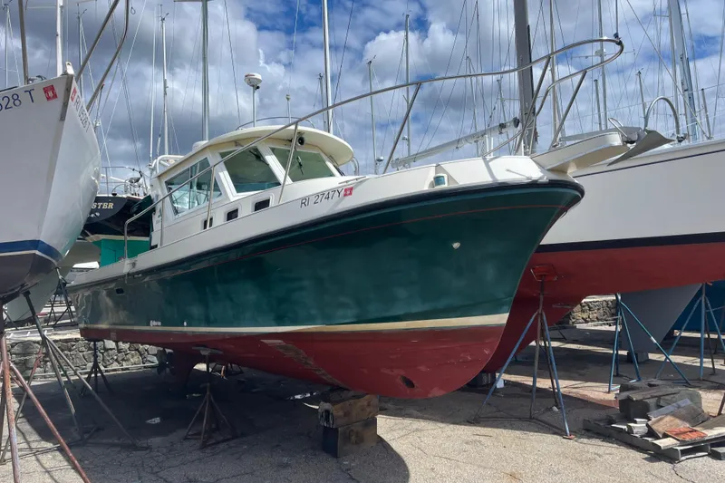 Slide: The Image of 1998 Albin 28 Tournament Express boat on dry dock, green hull, red bottom, marina background. - 4