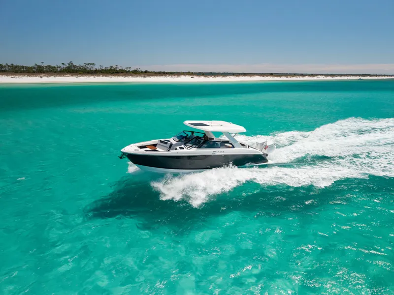 Slide: The Image of Cobalt R35 2024 boat cruising on turquoise waters near coastline. - 2