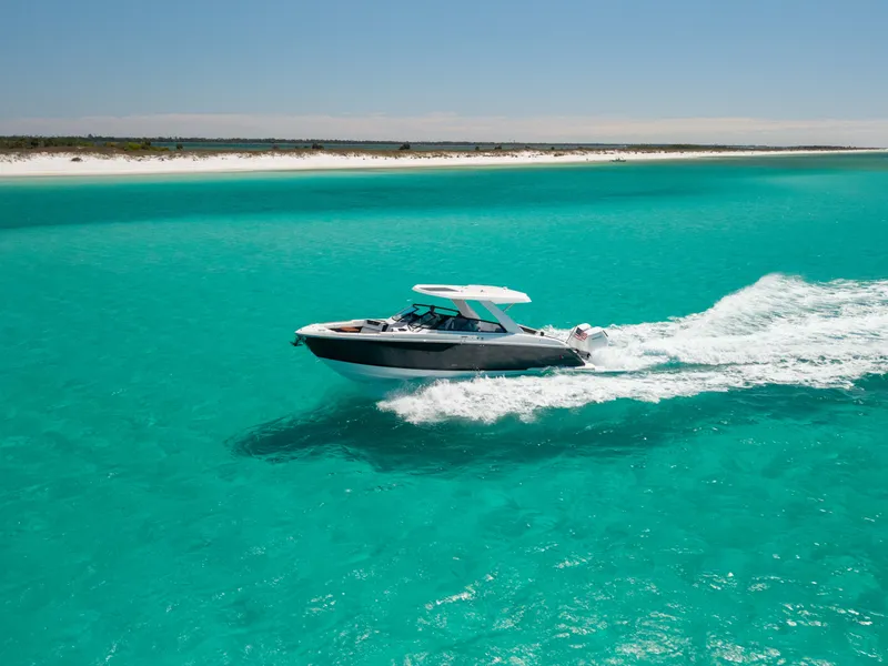 Slide: The Image of 2024 Cobalt R35 boat cruising on turquoise waters near coastline. - 3