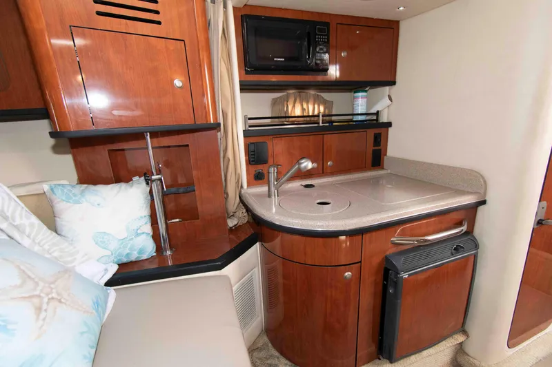 Slide: The Image of 2007 Sea Ray 290 Sundancer interior with kitchenette, featuring wood cabinetry and modern appliances. - 10