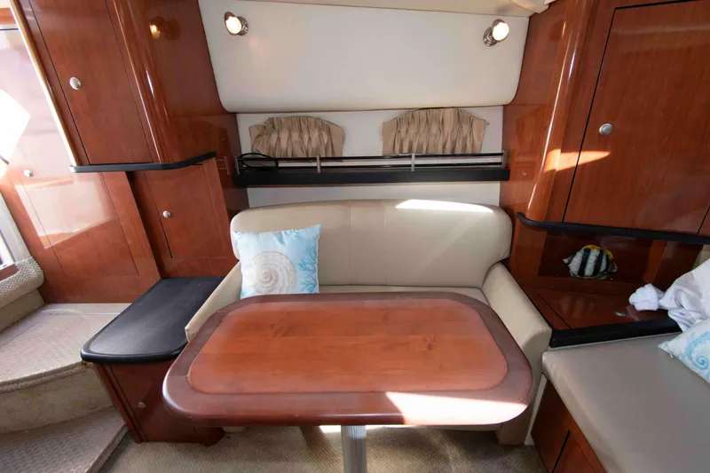 Slide: The Image of Interior of 2007 Sea Ray 290 Sundancer with wooden table and cushioned seating. - 11