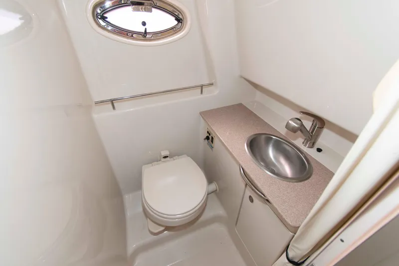 Slide: The Image of 2007 Sea Ray 290 Sundancer bathroom with toilet, sink, and porthole window. - 14