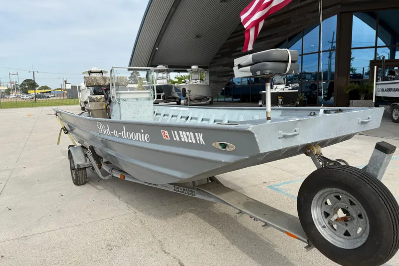 Slide: The Image of 2004 Tims Flat Boat 18x60 on trailer, parked outside with American flag. - 3