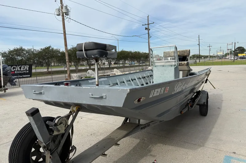 Slide: The Image of 2004 Tims Flat Boat 18x60 on trailer, parked outdoors, with visible seating and windshield. - 4