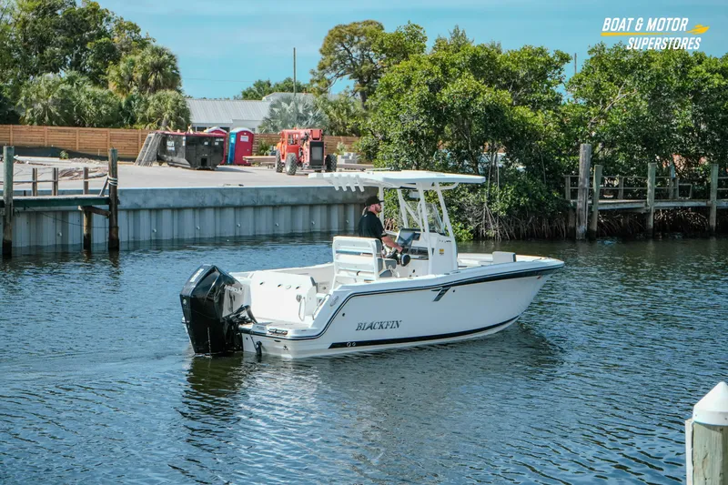 Slide: The Image of 2022 Blackfin 222 CC boat cruising on a calm waterway near a dock. - 51