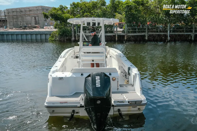 Slide: The Image of 2022 Blackfin 222 CC boat on water, rear view with outboard motor, near shoreline. - 56