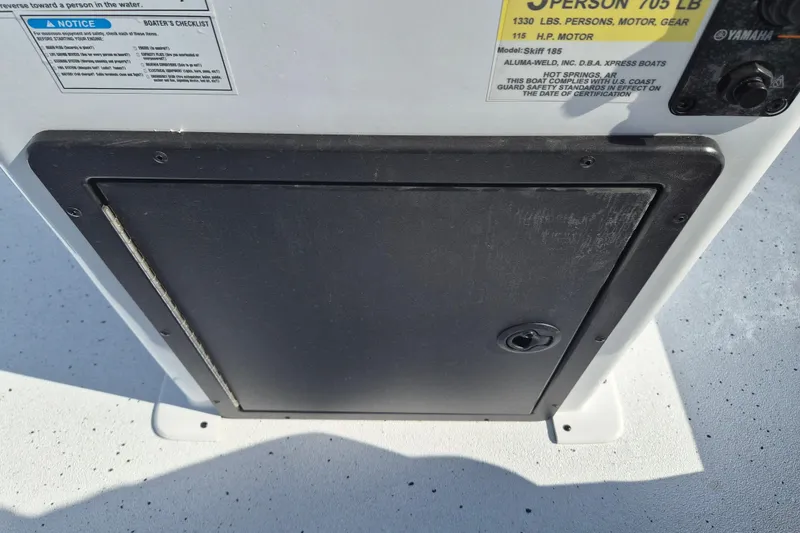 Slide: The Image of 2026 Xpress Skiff 185 boat compartment with safety and capacity labels. - 12