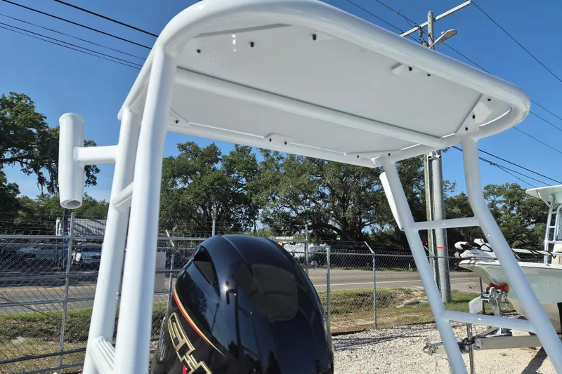 Slide: The Image of 2026 Xpress Skiff 185 boat with T-top and outboard motor, parked outdoors. - 6