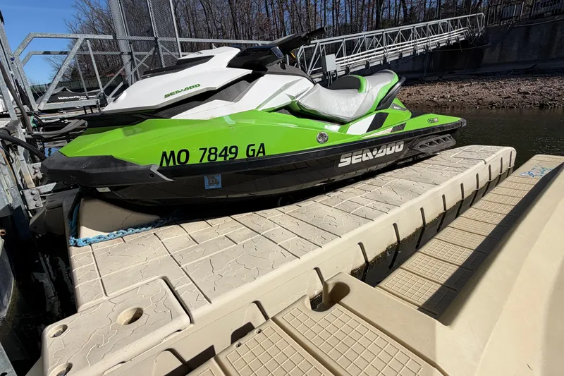 Slide: The Image of 2014 Sea-Doo GTI 130 jet ski in green, docked on a sunny day. - 11