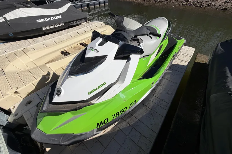 Slide: The Image of 2014 Sea-Doo GTI 130 jet ski in vibrant green, docked by the water. - 13