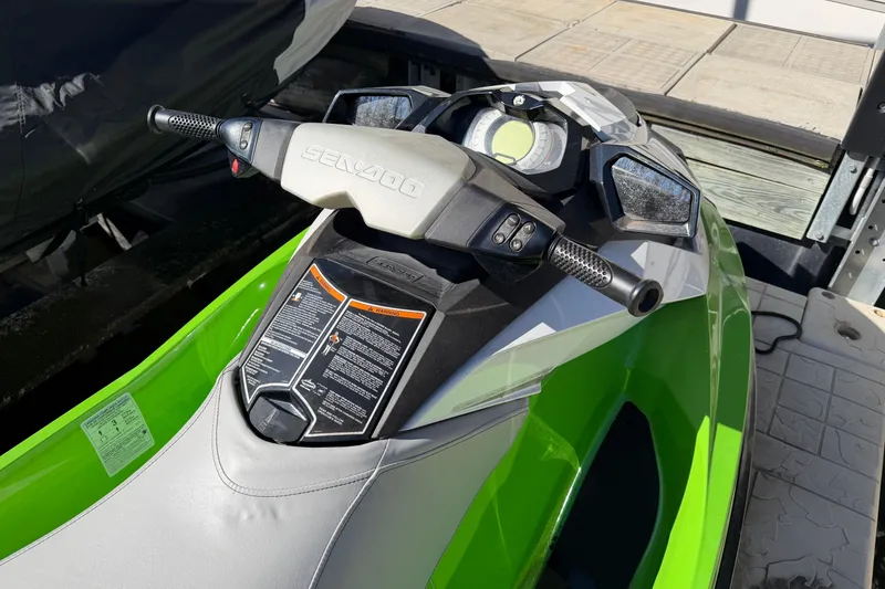 Slide: The Image of 2014 Sea-Doo GTI 130 jet ski with green and gray design, docked outdoors. - 20