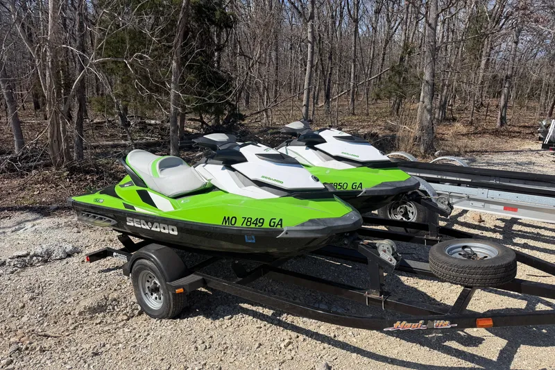The Image of 2014 Sea-Doo GTI 130 jet skis on trailer in wooded area. - 3