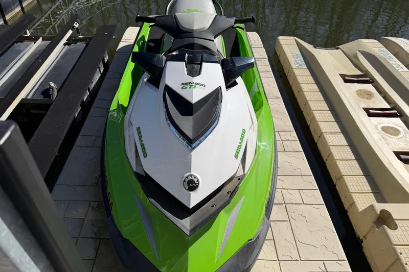 Slide: The Image of 2014 Sea-Doo GTI 130 jet ski in vibrant green and white, docked by the water. - 8