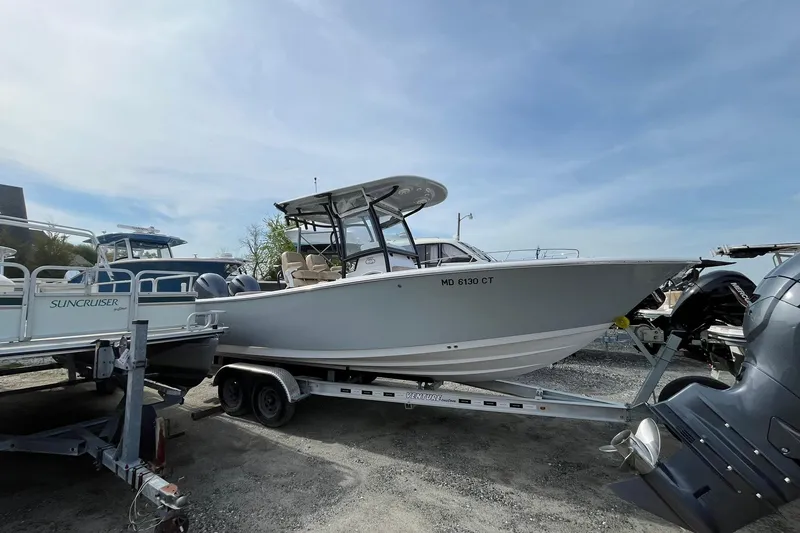 The Image of 2020 Sportsman Open 252 Center Console boat on trailer, parked outdoors. - 1