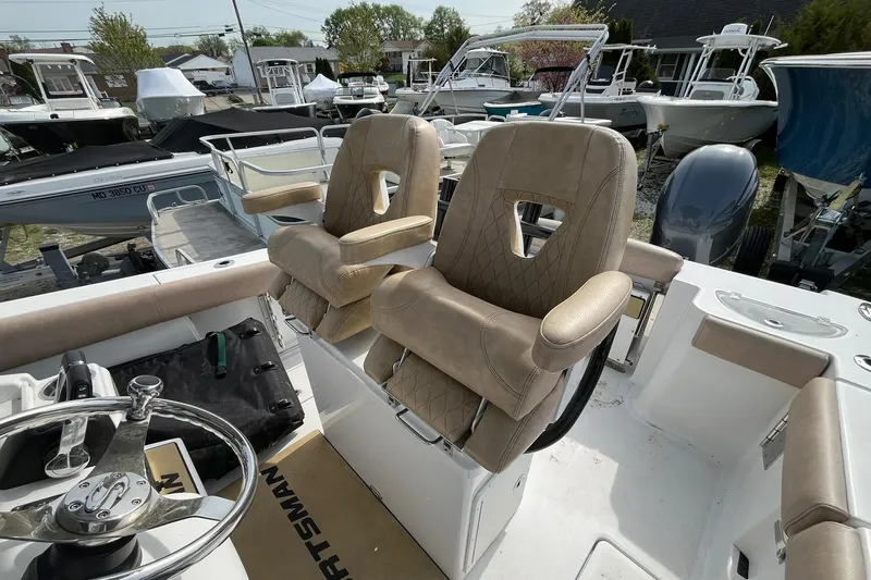 Slide: The Image of 2020 Sportsman Open 252 Center Console boat with beige seating and steering wheel. - 15