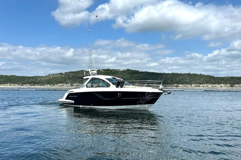 Slide: The Image of 2017 Monterey 360 Sport Coupe yacht cruising on a serene lake under a partly cloudy sky. - 8