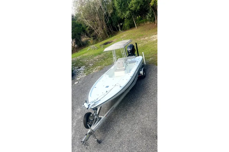 The Image of 2017 Yellowfin 21 Hybrid boat on trailer, parked on a gravel path near trees. - 1