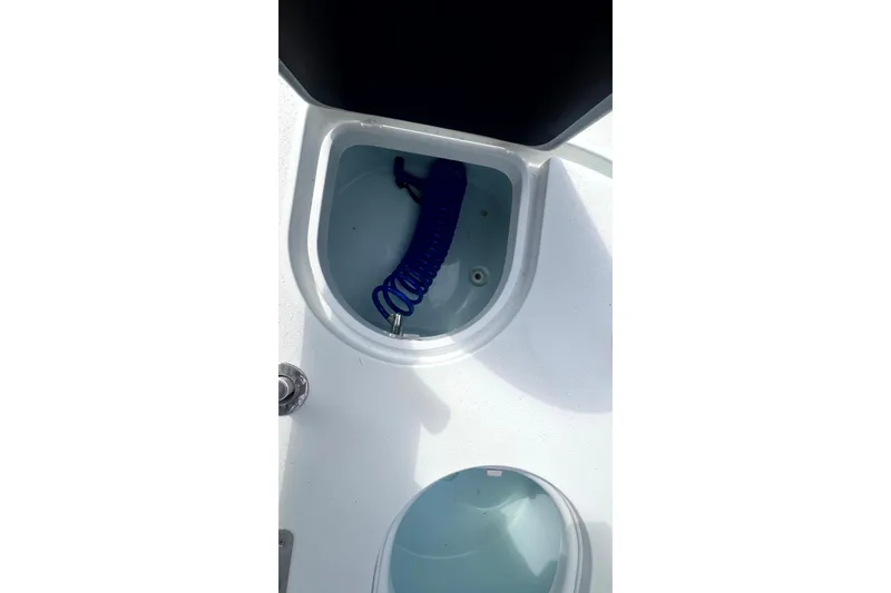 Slide: The Image of Storage compartment with blue hose on 2017 Yellowfin 21 Hybrid boat. - 16