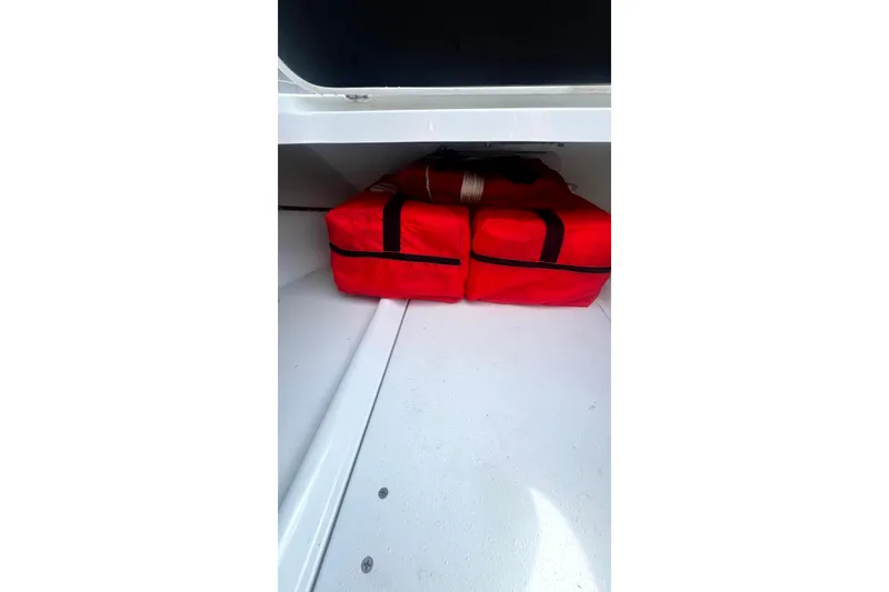 Slide: The Image of Storage compartment with red bags on a 2017 Yellowfin 21 Hybrid boat. - 7