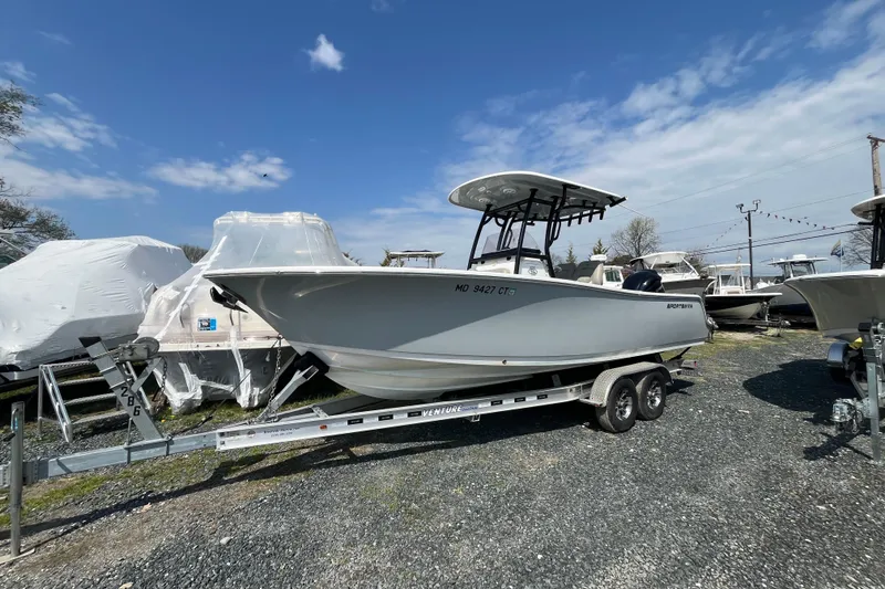 The Image of 2022 Sportsman Open 242 Center Console boat on trailer under clear sky. - 1