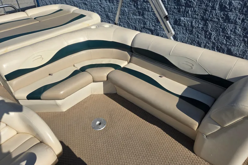 Slide: The Image of 2004 Bennington 257L boat interior with beige and green seating, showcasing luxury design. - 4