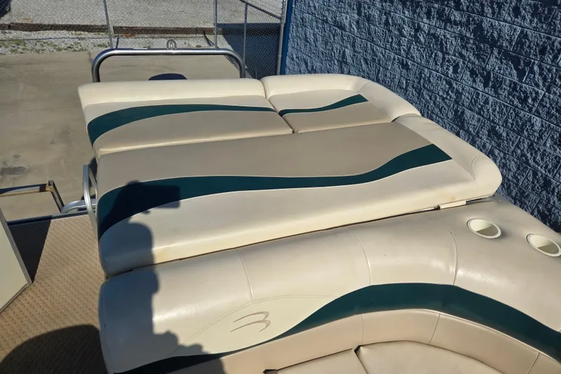 Slide: The Image of 2004 Bennington 257L boat with beige and green cushioned seating, featuring cup holders. - 5