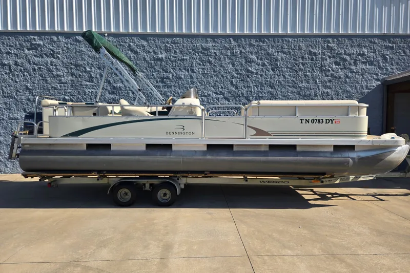 Slide: The Image of 2004 Bennington 257L pontoon boat on trailer, parked outdoors. - 6
