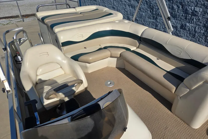 Slide: The Image of 2004 Bennington 257L pontoon boat interior with beige and green seating. - 7