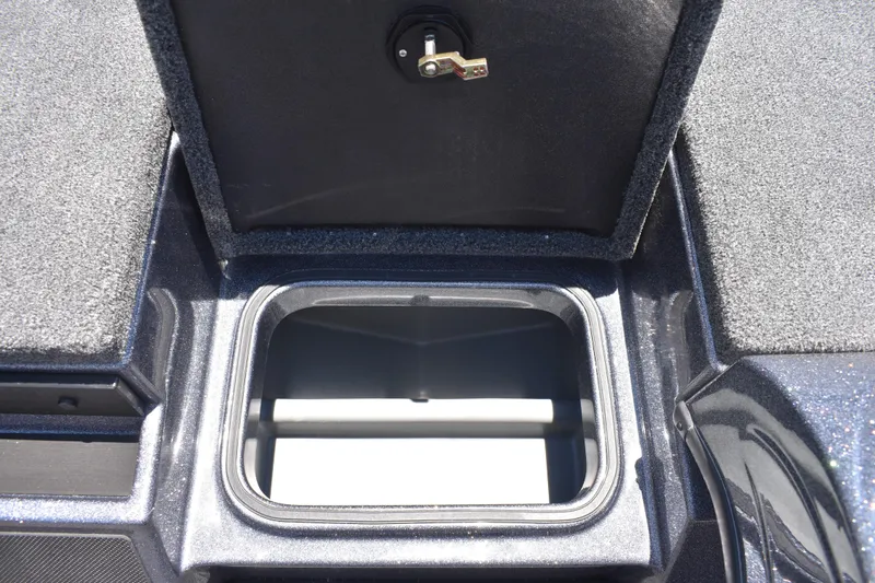 Slide: The Image of Open storage compartment on 2026 Triton 179 TrX boat, featuring secure latch and carpeted interior. - 24